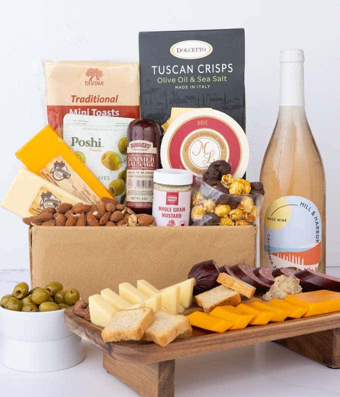 An abundent gift box filled with California Rosé Wine, assorted crackers, two cheeses, summer sausage, and snacks to make an amazing charcuterie spread. 