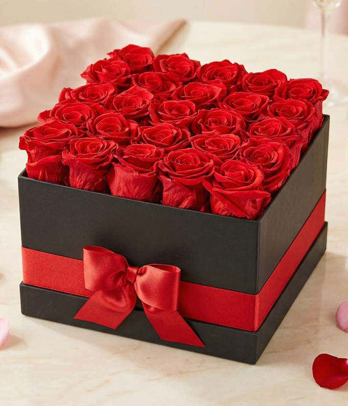 25 preserved red roses arranged into a black hat box with a red ribbon.