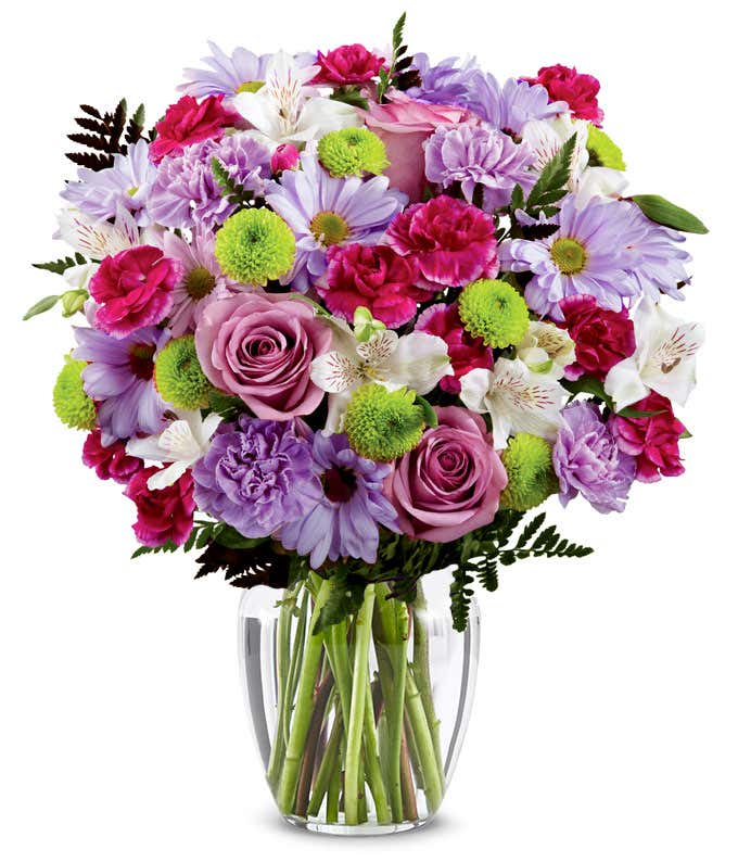 A bouquet featuring lavender daisies, lavender roses, hot pink mini carnations, lavender carnations, white alstroemeria, and green button poms, with an optional vase.