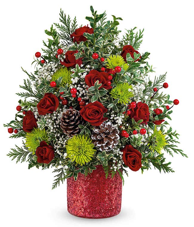 Christmas tree-shaped floral arrangement with red roses, green button spray chrysanthemums, white limonium, red berry spray, pinecones, and greenery in a red glittered container.
