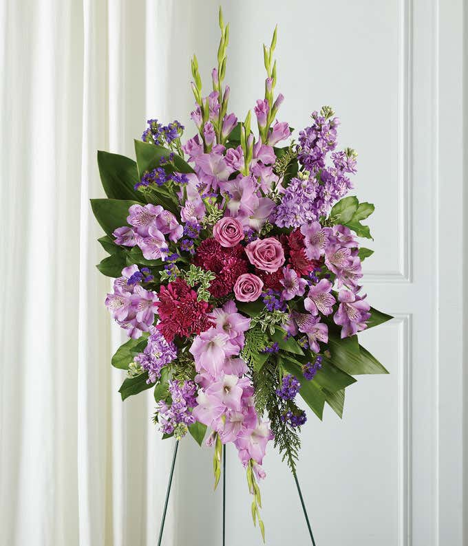 A stunning standing funeral spray featuring purple spray roses, purple alstroemeria, purple gladiolus, purple cushion mums, and sinuata statice. This elegant and monochromatic arrangement offers a beautiful and respectful tribute.