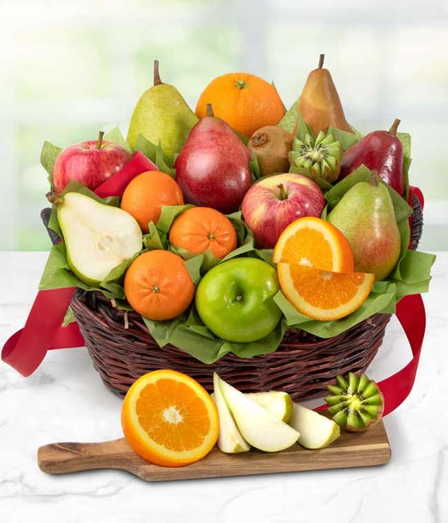 A basket filled to the brim with apples, pears, kiwis, and oranges with a green ribbon tied in a bow at the front.