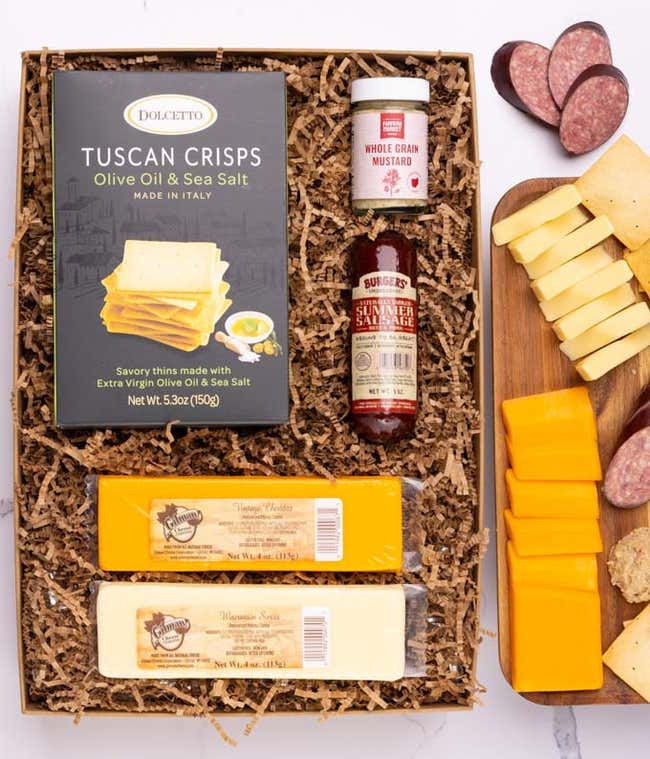 A charcuterie box with two types of cheese, crackers, stone-ground mustard, and a summer sausage.