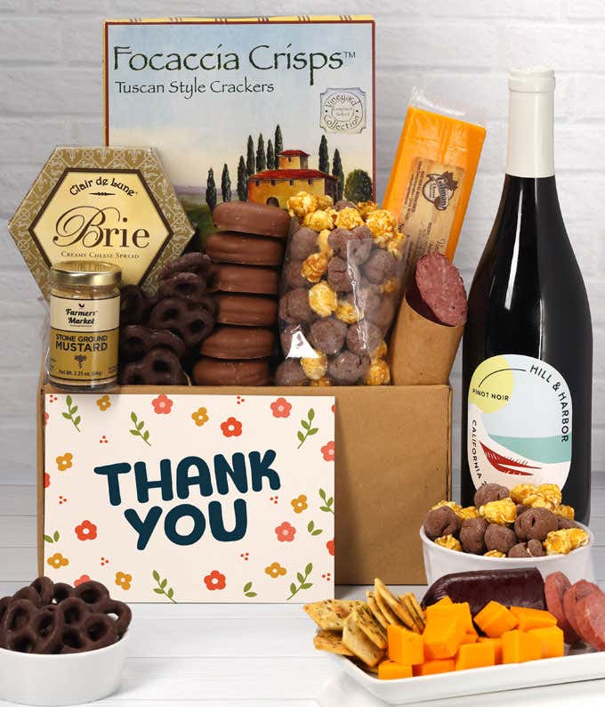 A gift set featuring a bottle of California Pinot Noir, focaccia crisps, two cheeses, mustard, summer sausage, caramel popcorn, chocolate pretzels, six chocolate-covered Oreos and a Thank You card to complete the gourmet experience.