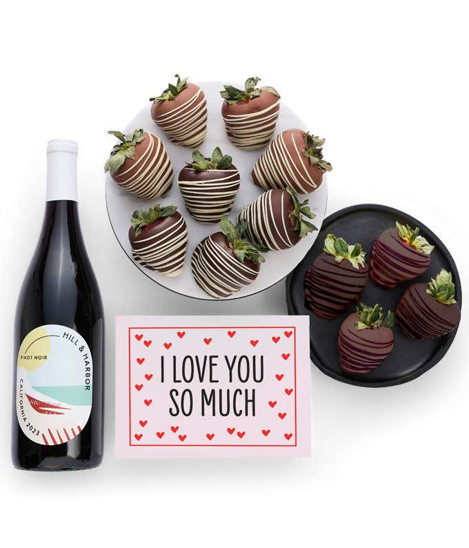 A bottle of Hill & Harbor California Pinot Noir is displayed beside 12 assorted chocolate-covered strawberries, drizzled in milk and dark chocolate and a card saying, 'I Love You'.