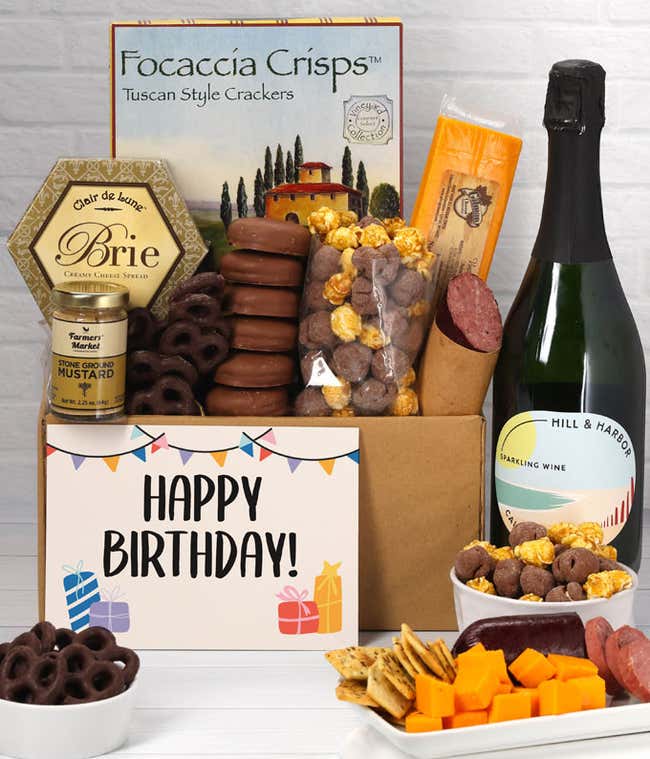 A gift set featuring a bottle of California Sparkling Wine, focaccia crisps, two cheeses, mustard, summer sausage, caramel popcorn, chocolate pretzels, six chocolate-covered Oreos and a Birthday card to complete the gourmet experience.