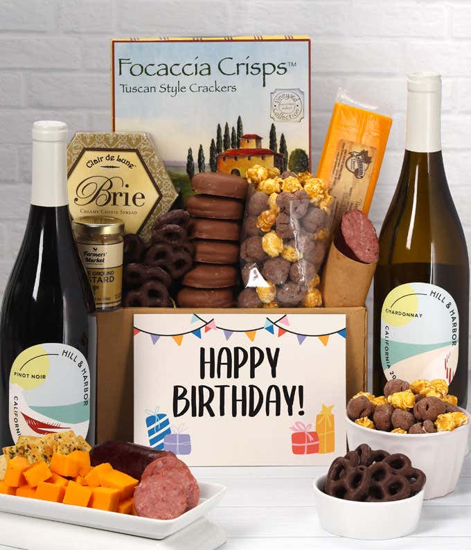 A gift set featuring two bottles of Hill & Harbor wine - white and red, focaccia crisps, two cheeses, mustard, summer sausage, caramel popcorn, chocolate pretzels, six chocolate-covered Oreos and a Birthday card to complete the gourmet experience.